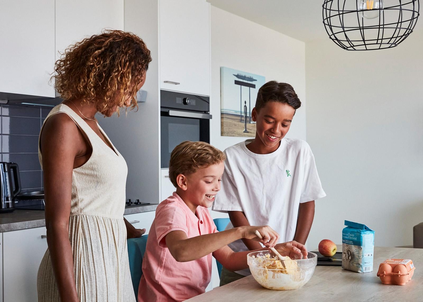 Een mama met haar twee kinderen aan het bakken in een vakantieappartement van Holiday Suites