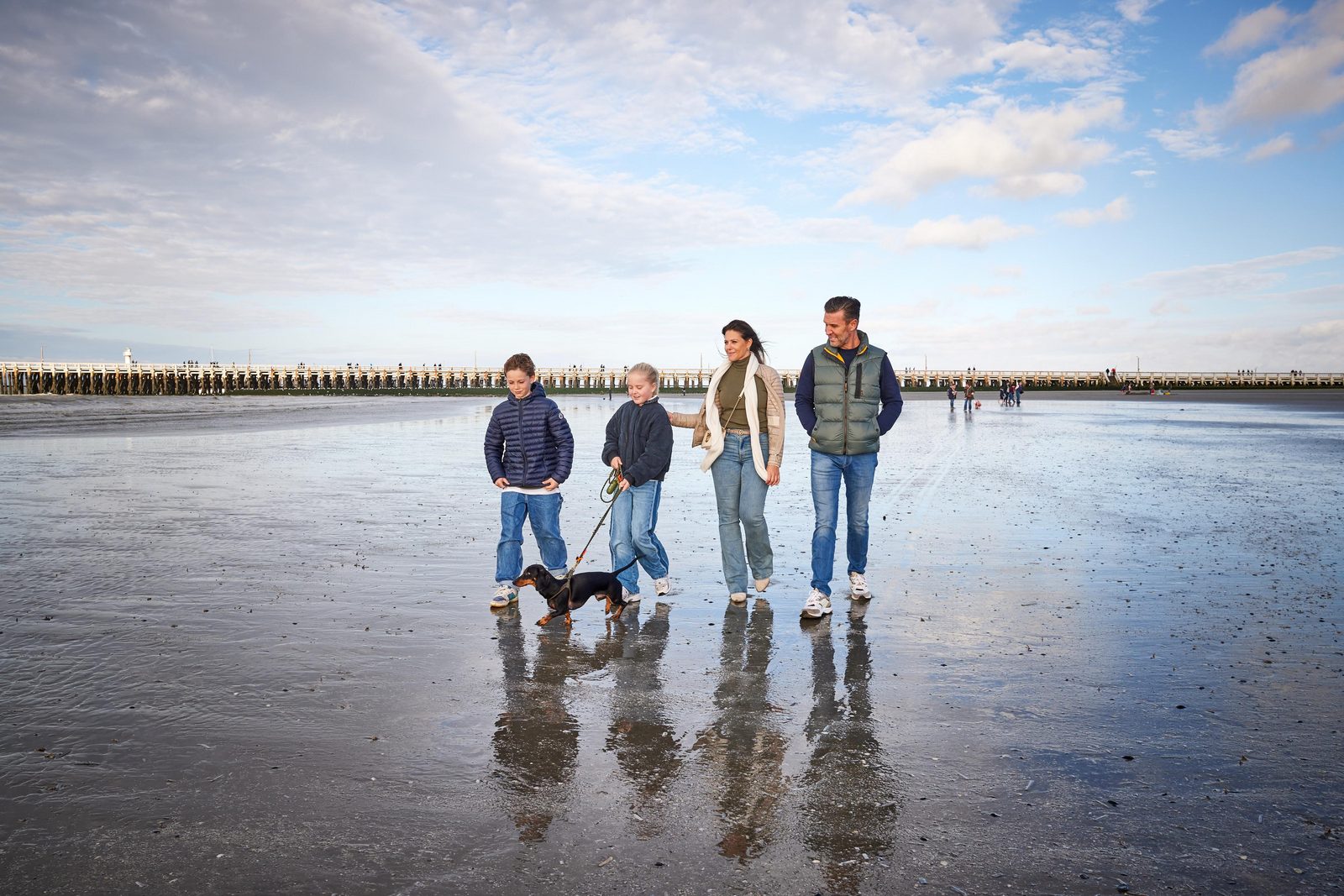 Familie met een hond die op het strand loopt dichtbij onze residentie in Nieuwpoort