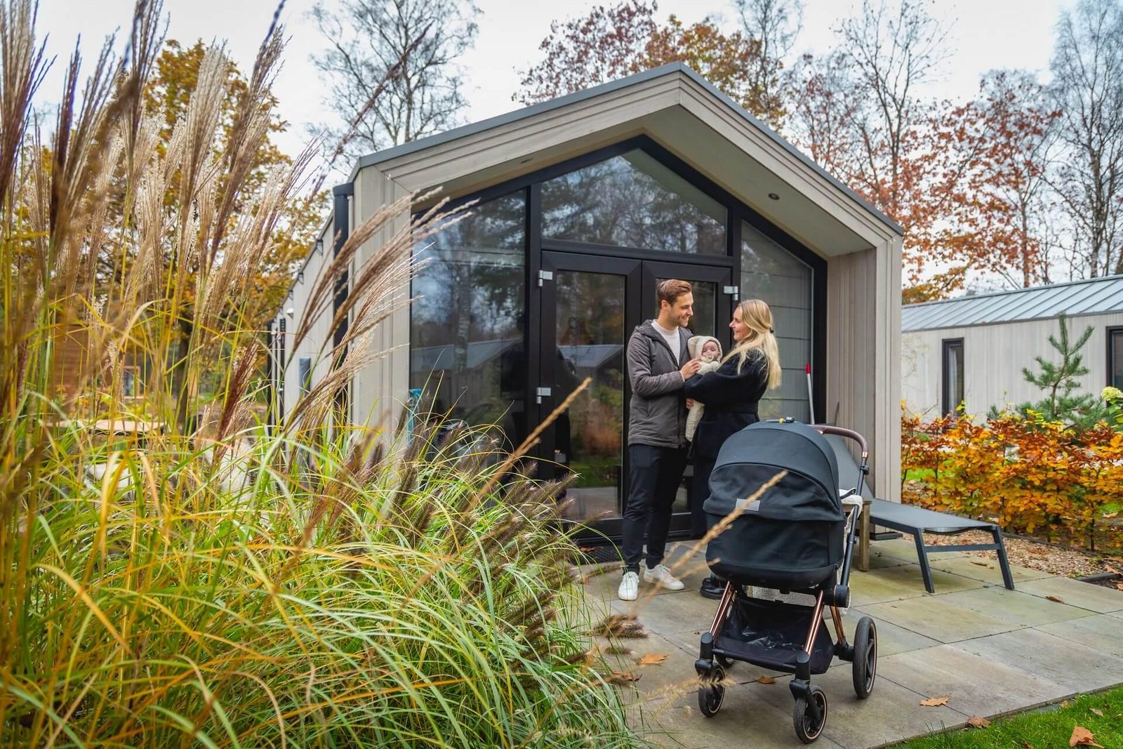 Baby friendly holidays - couple with baby infront of the holiday cottage at holiday park De Hooge Veluwe