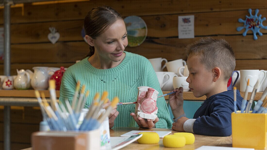 Interior of a ceramic painting studio: shelves lined with blank pottery pieces and a worktable ready for creative decoration.