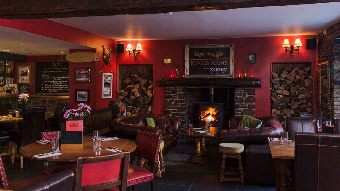 The Kings Arms, Georgeham Traditional British pub interior with fireplace, leather seating, dining tables, and warm cozy atmosphere.
