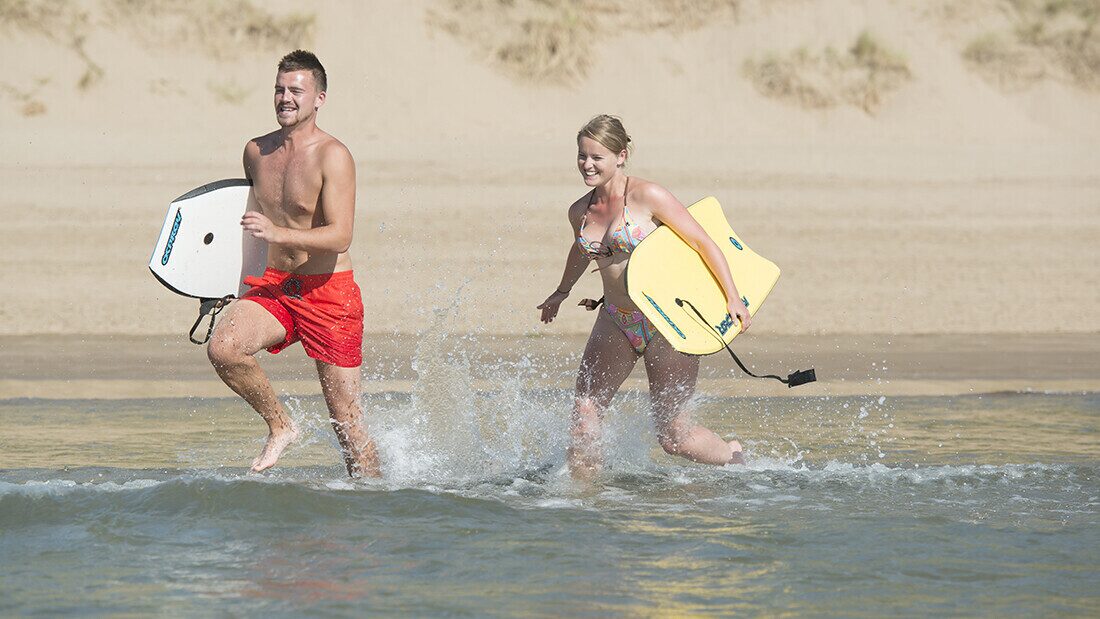 Make the most of good weather if you're flexible Couple enjoying bodyboarding and running into the sea on Woolacombe Beach in North Devon