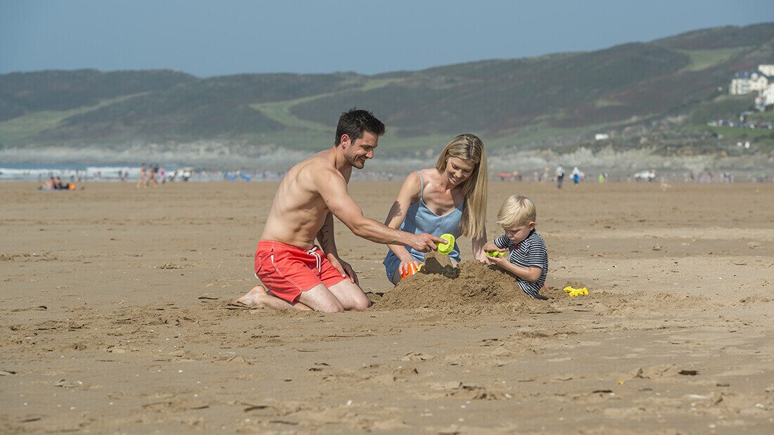 Beaches provide hours of free fun Young family building sandcastles on Woolacombe Beach in North Devon on a sunny day.