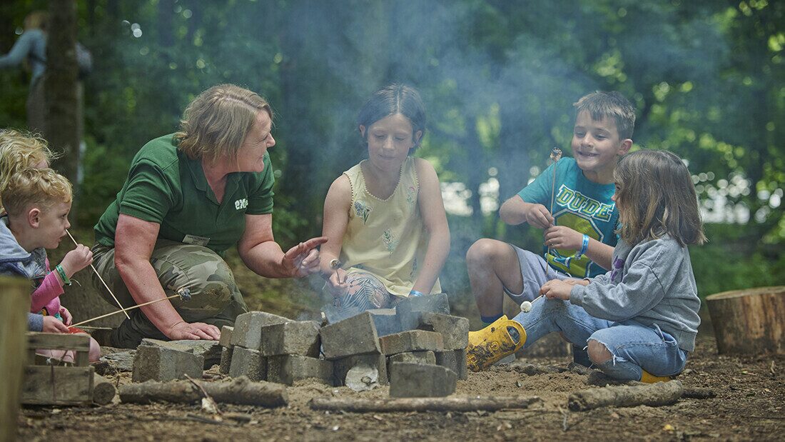 Look out for low cost activities that are fun and last a while Children roasting marshmallows around a campfire during outdoor family nature activities