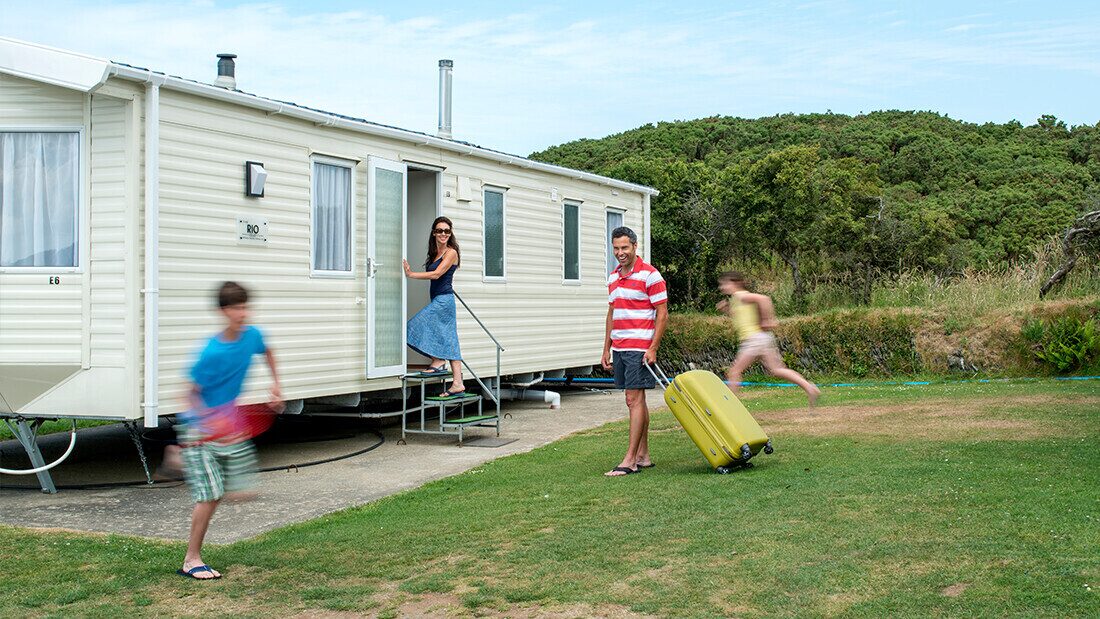 Bring all you need - no luggage limits or charges Family arriving at a holiday caravan with luggage, ready to start their stay at a UK holiday park