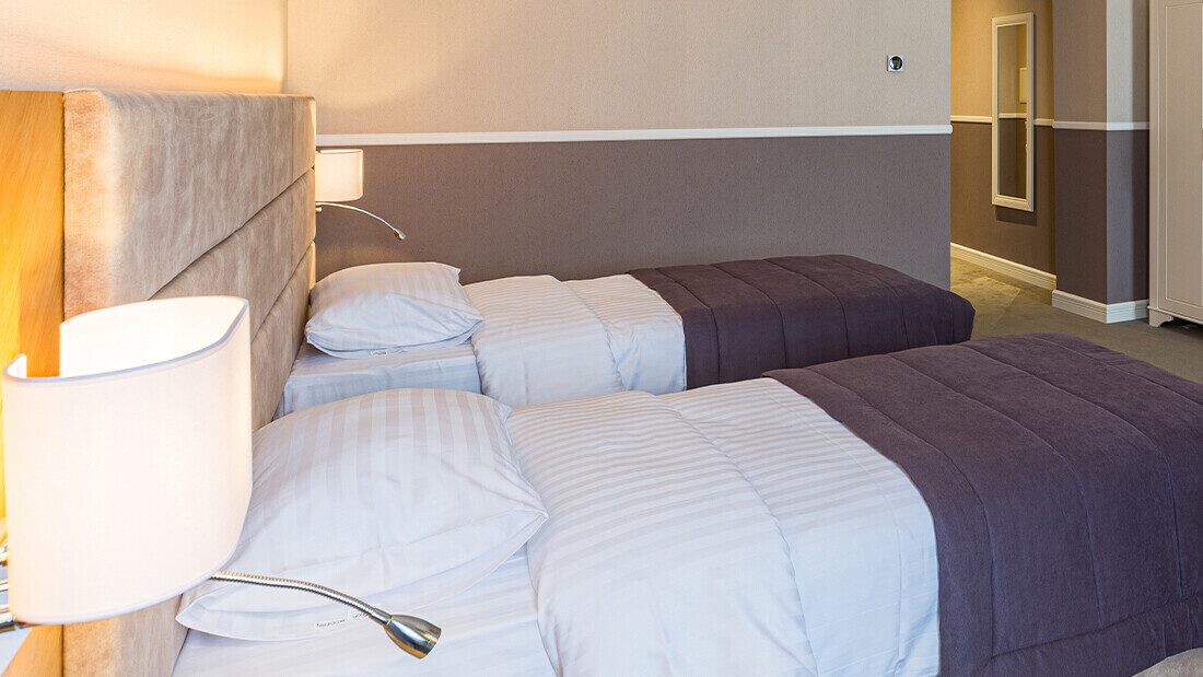 Budget hotel bedrooms provide little in the way of amenities Twin bedroom in a budget-friendly holiday park hotel in Devon with modern decor and comfortable beds.