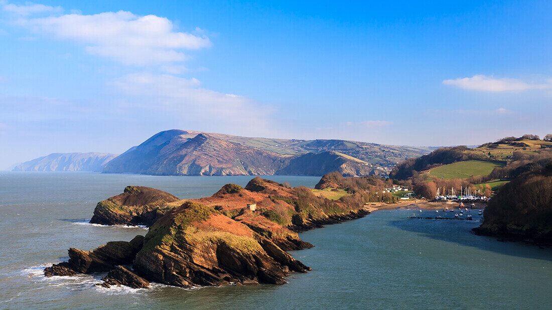Scenic view of Watermouth Cove in North Devon with rugged cliffs, blue sea, and rolling countryside