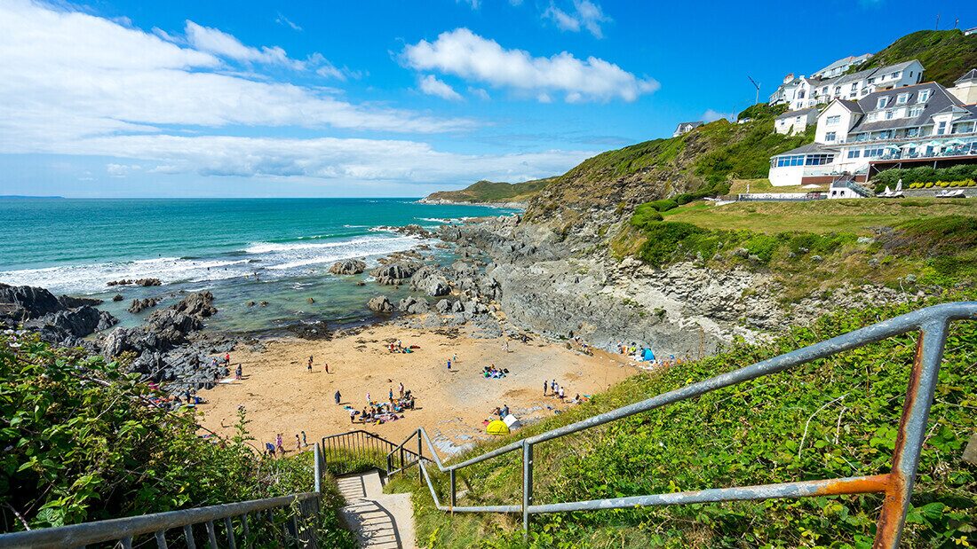 Scenic view of Combesgate Beach near Woolacombe in North Devon with families enjoying the sandy cove, rocky cliffs, and turquoise sea.