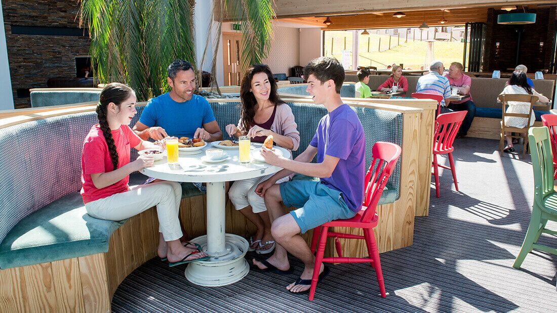 Family enjoying breakfast at a holiday park restaurant near Woolacombe, perfect for Devon family breaks with on-site dining.