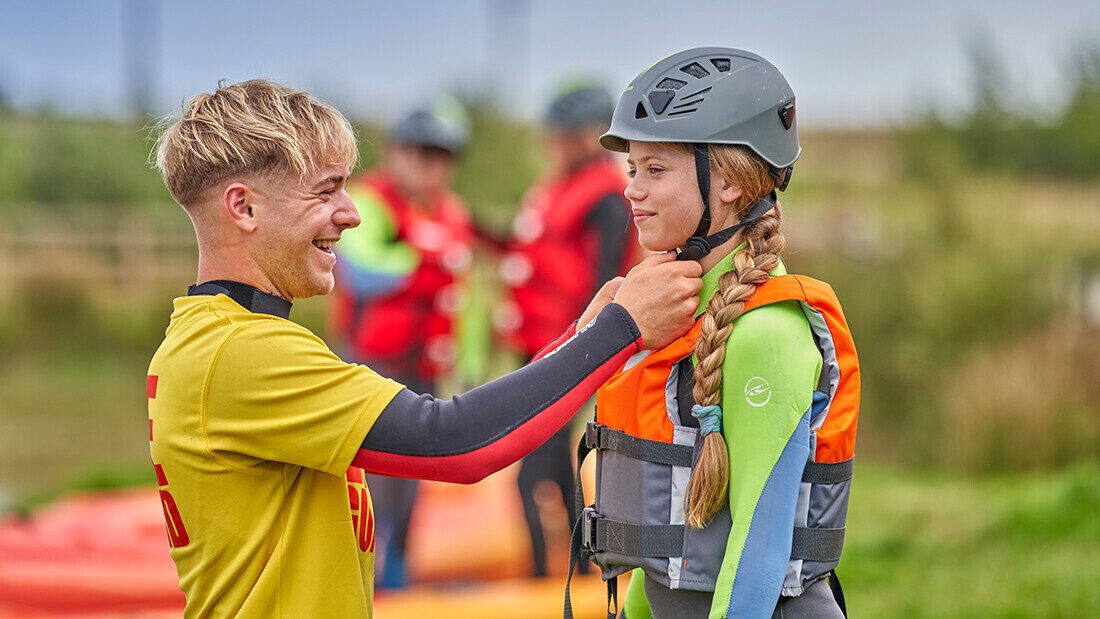 Instructor helping child prepare for outdoor adventure activity at Woolacombe Bay Holiday Parks