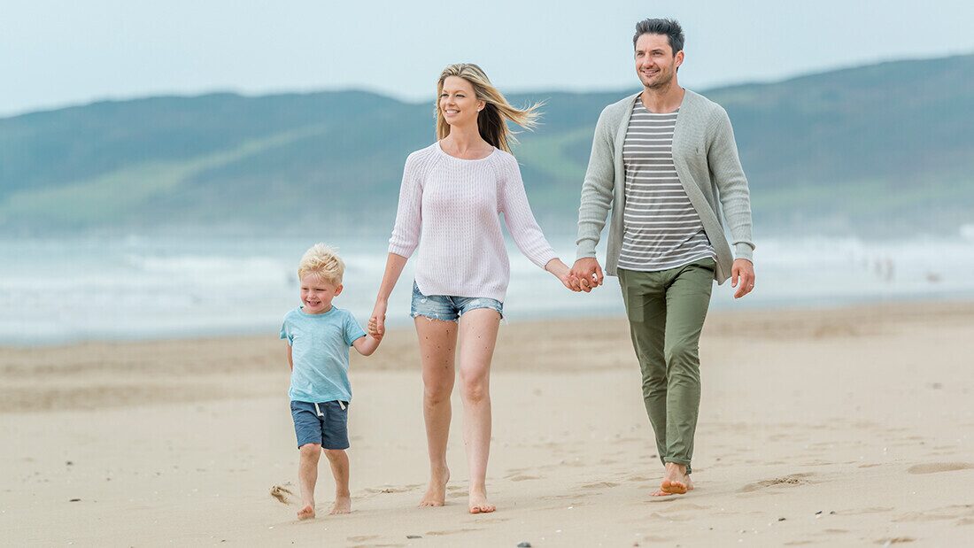 Family stroll on Woolacombe Beach during a seaside holiday in North Devon. Family walking along Woolacombe Beach enjoying a seaside holiday in North Devon