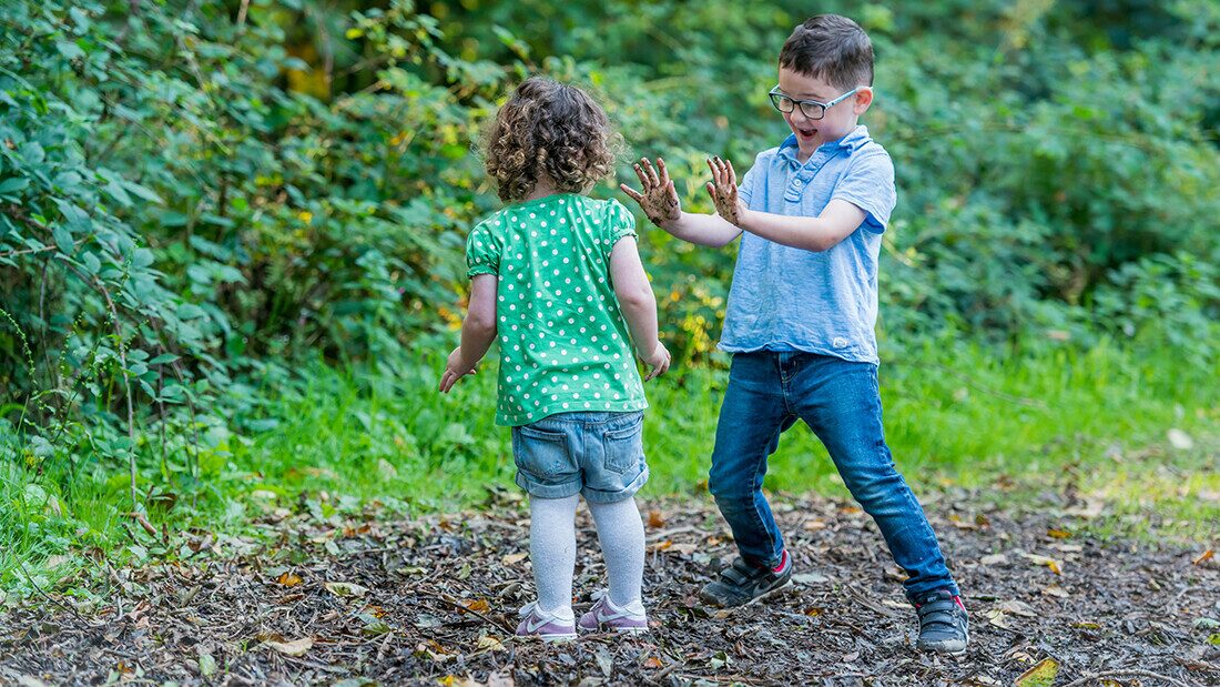 Boy and guy playing in mud Young children playing with mud and enjoying outdoor adventures in the woodland