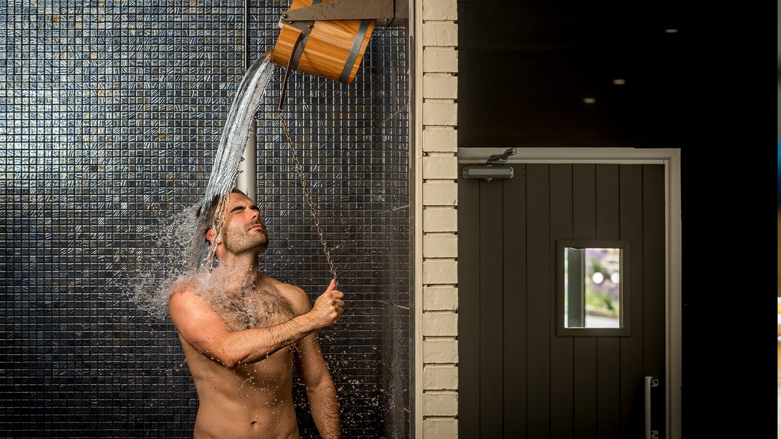 man dropping water on himself from a cold drenching bucket in Woolacombe Bay spa