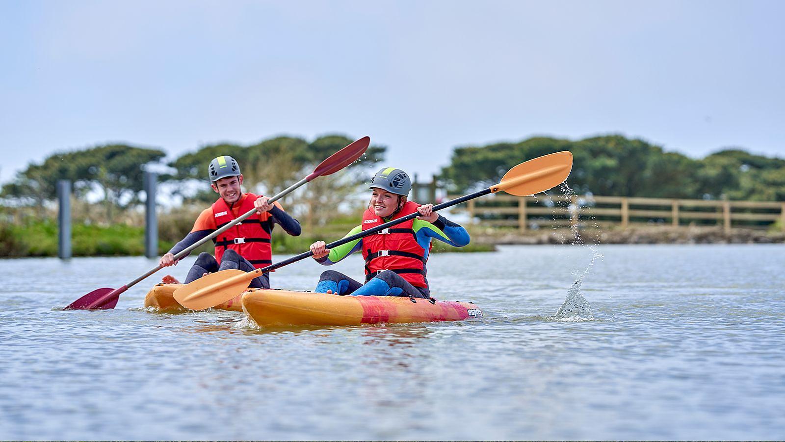 Young couple on kayaks on water sports activity lake at Woolacombe Bay Holiday Park