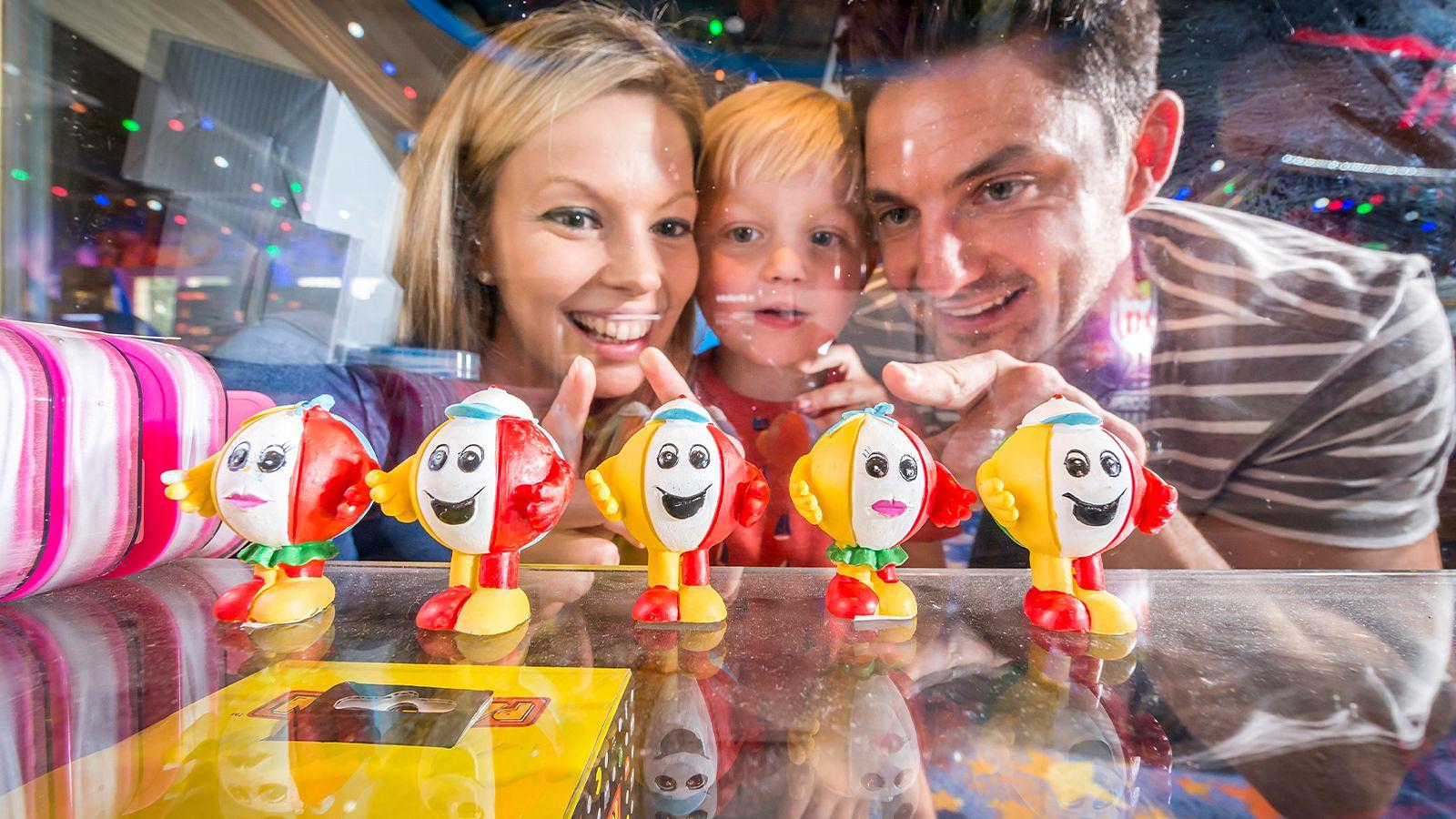 Boy and parents looking at Billy beachball toys in the prize shop at Woolacombe Bay Holiday Parks