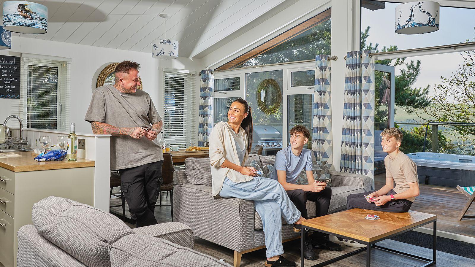 A group of four family members relaxing inside a luxury lodge with hot tub at Woolacombe Bay Holiday Park