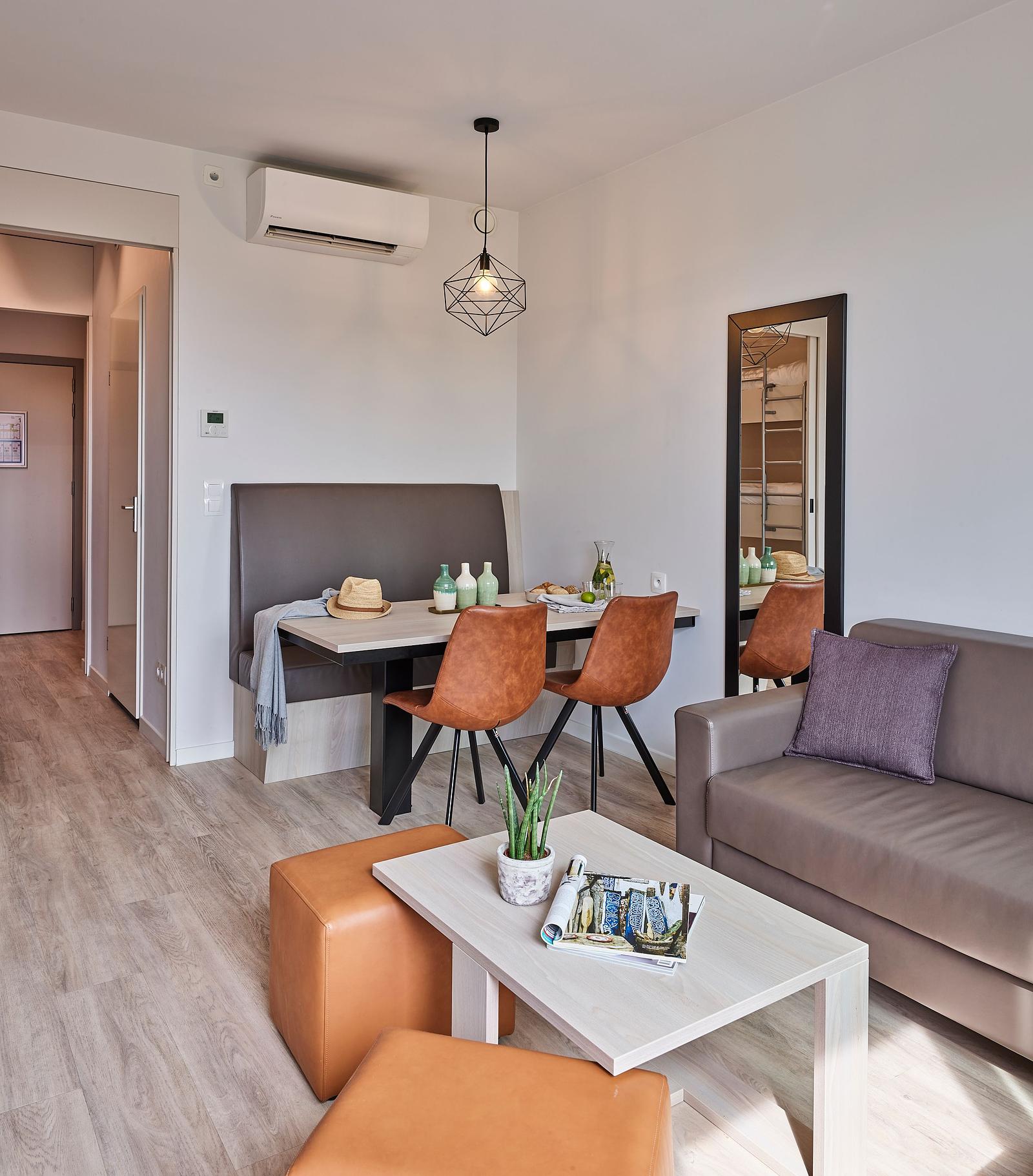 Suite de vacances moderne et chaleureuse chez Holiday Suites avec coin repas, coin salon confortable et intérieur élégant, idéale pour un séjour relaxant sur la côte belge.