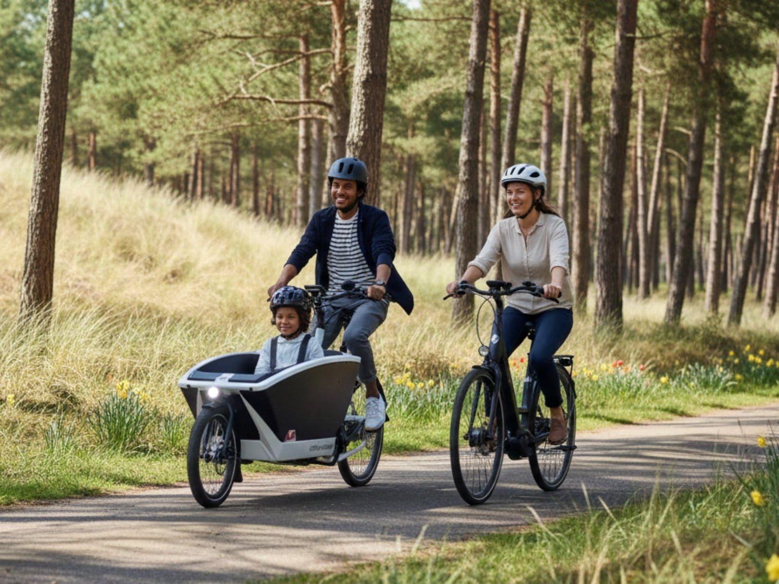 Familie op een Urban Arrow elektrische bakfiets in het bos op Texel bij Vakantiepark De Witteberg.