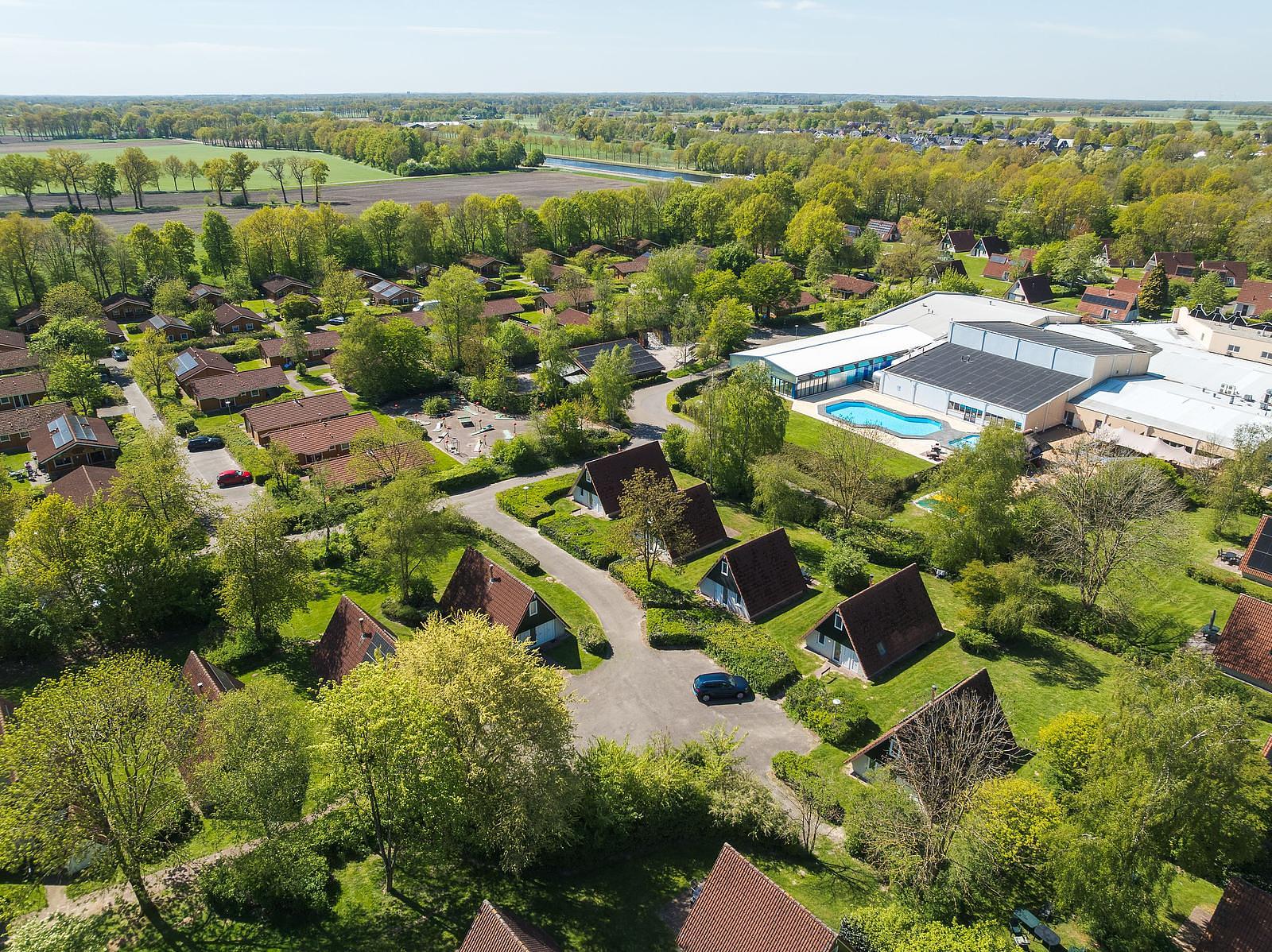 Vogelperspektive auf den günstigen Ferienpark in Holland. Zu sehen sind das Schwimmbad und die im Grünen gelegenen Ferienhäuser