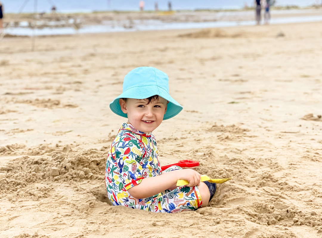 Beach Day Child with a blue hat digging sand on a beach