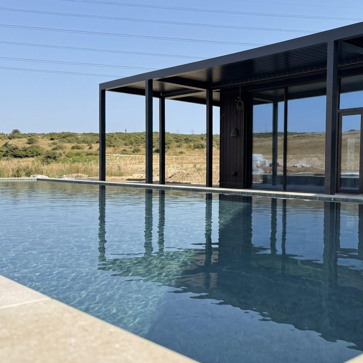 The 25-metre heated outdoor pool at Firefly Spa, Silverlake Estate, Dorset, offering year-round outdoor swimming in a peaceful lakeside wellness setting.