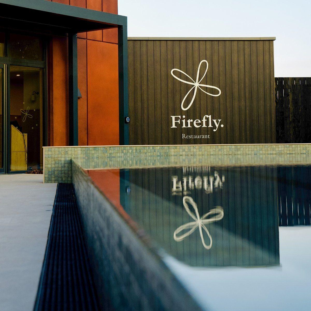 Firefly Restaurant overlooking Firefly Spa's 25m heated outdoor pool at Silverlake, Dorset, with the modern building reflected in the still water.