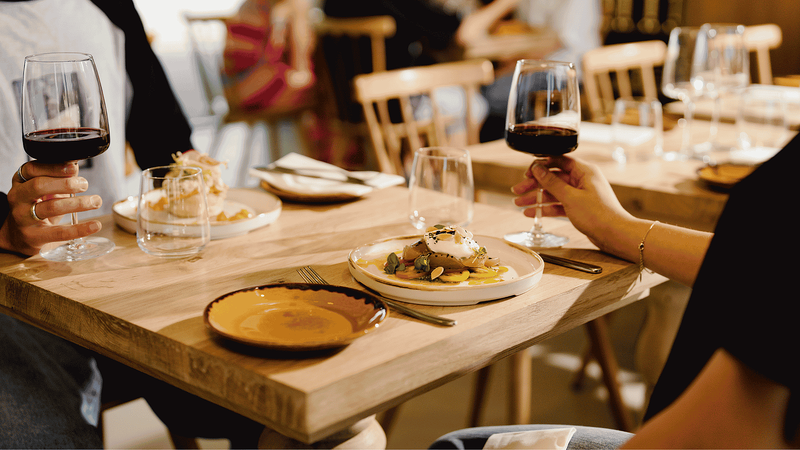 Guests dining at a wooden table in Firefly Restaurant at Silverlake Estate, Dorset, with seasonal dishes and glasses of red wine.