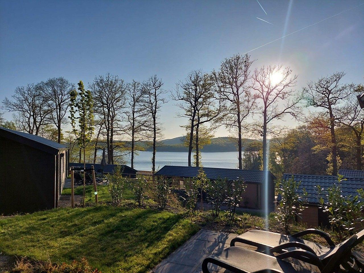 Der Biggesee beim Ferienpark mit Camping nahe Olpe, die Sonne geht gerade auf und scheint durch die leicht kahlen Bäume 