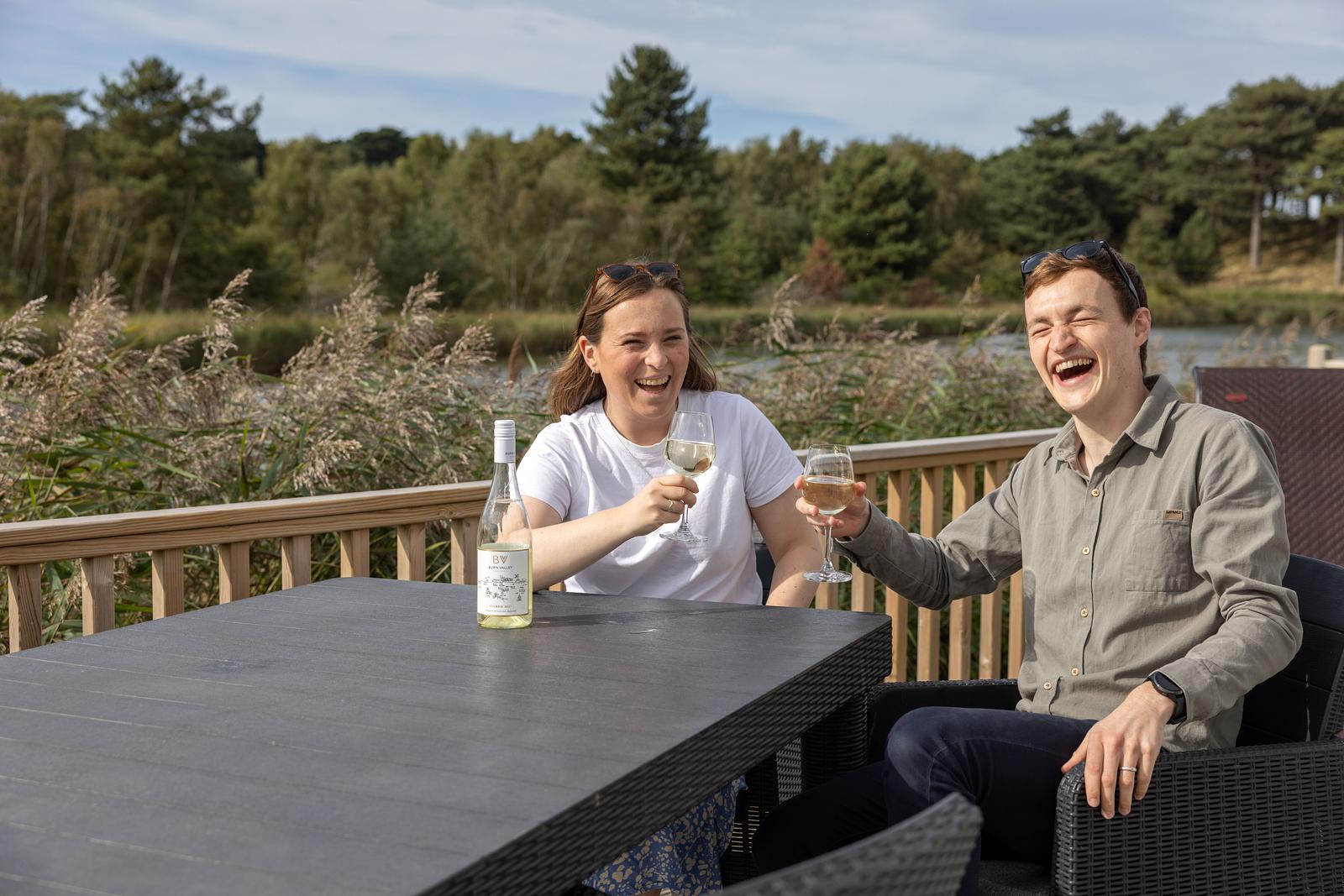 Couple laugh on the decking on a holiday at Pinewoods