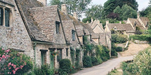Historic stone cottages along Arlington Row in Bibury, surrounded by cottage gardens and greenery