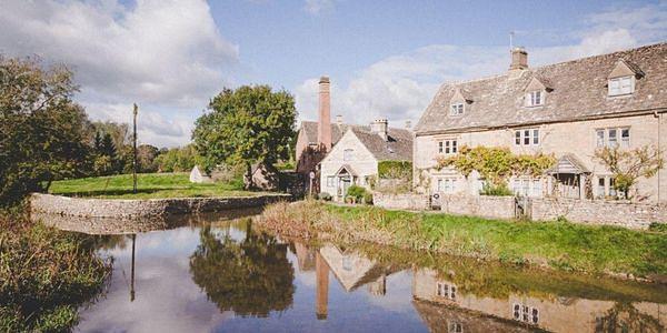 Traditional Cotswold stone cottages reflected in the River Eye in Lower Slaughter