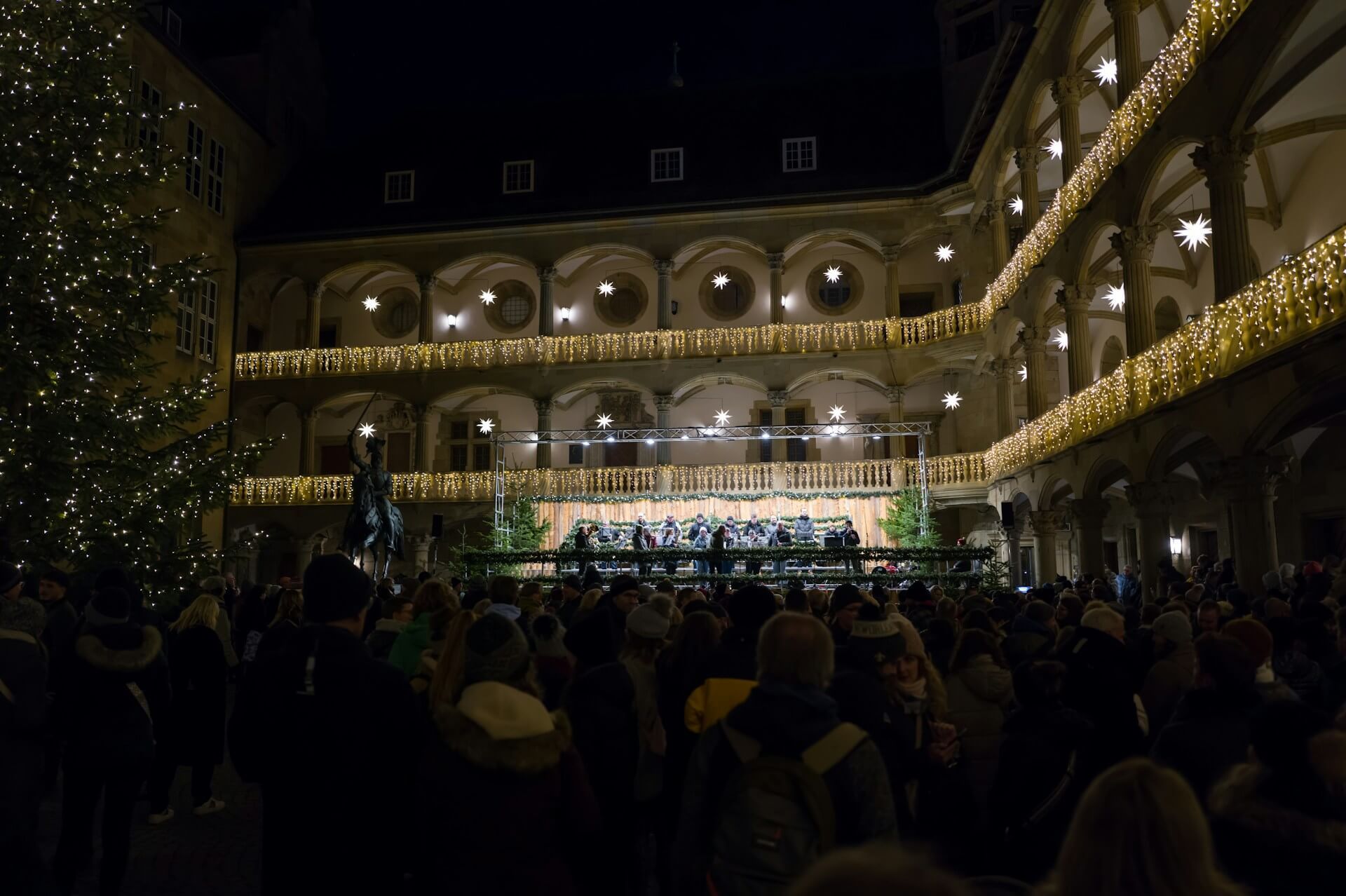 Bezoekers tussen de verlichte kraampjes van een kerstmarkt, sfeerbeeld bij de kerstmarkten in Münster