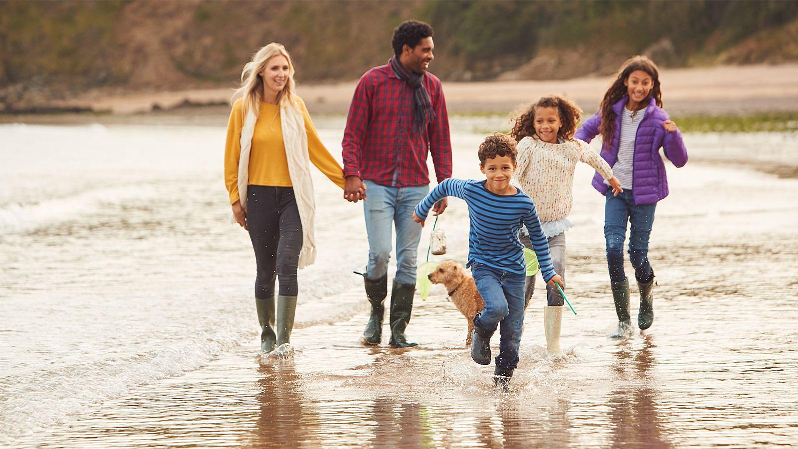 A family with dog run in the sea on an Autumn day