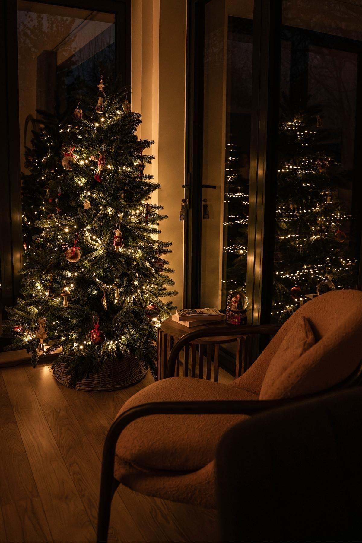 Warmly lit Christmas tree beside a cosy seating area within a lakeside holiday home at Lower Mill Estate, The Cotswolds.