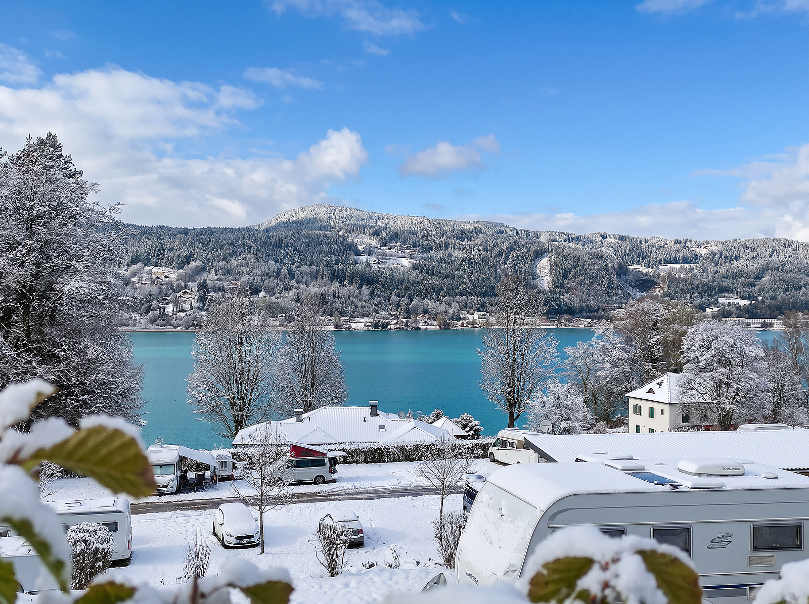 Lake Wörthersee in the snow, with snow-covered RVs in the foreground