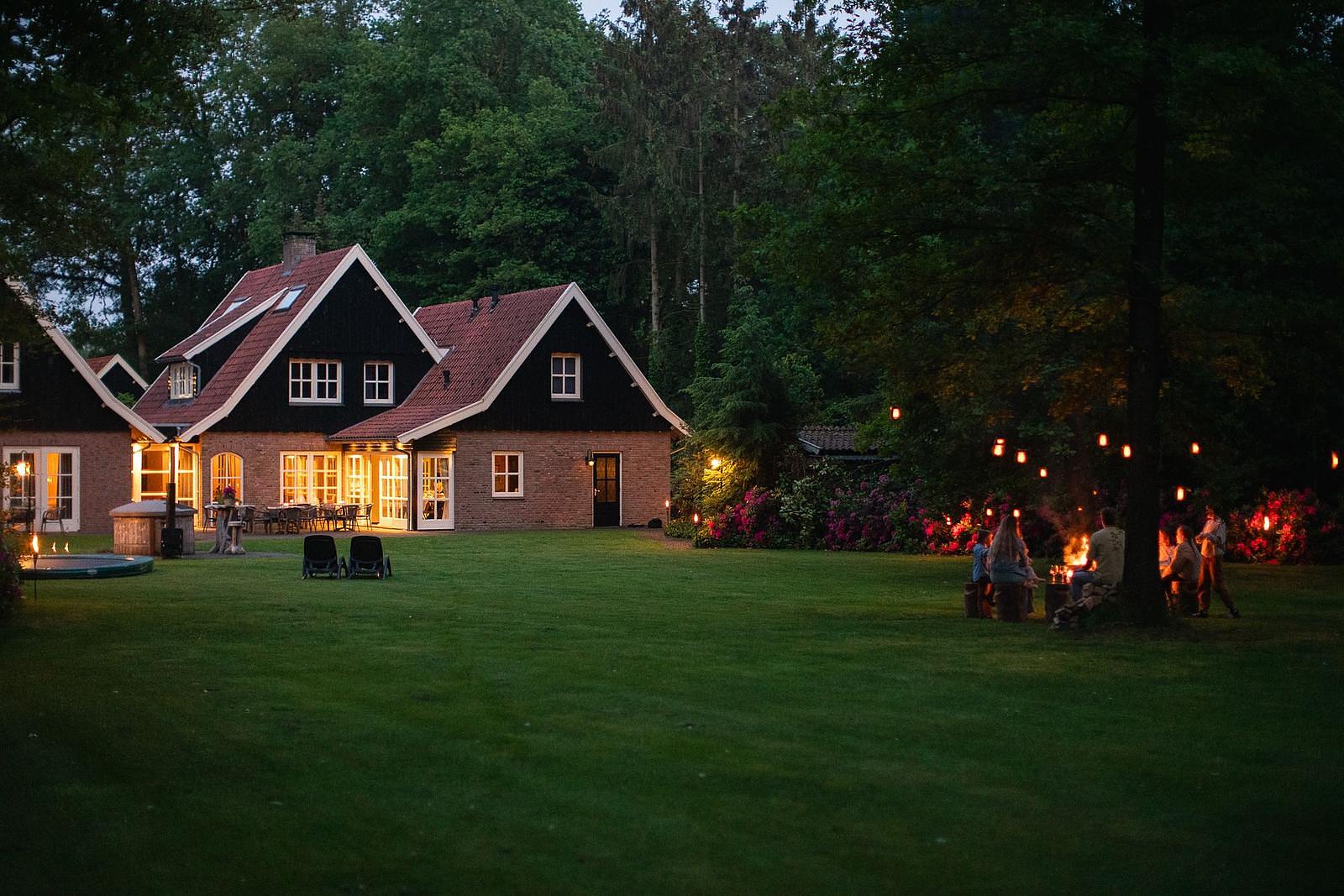 Het Landhuis mit beleuchteten Fenstern und Lagerfeuer im Garten